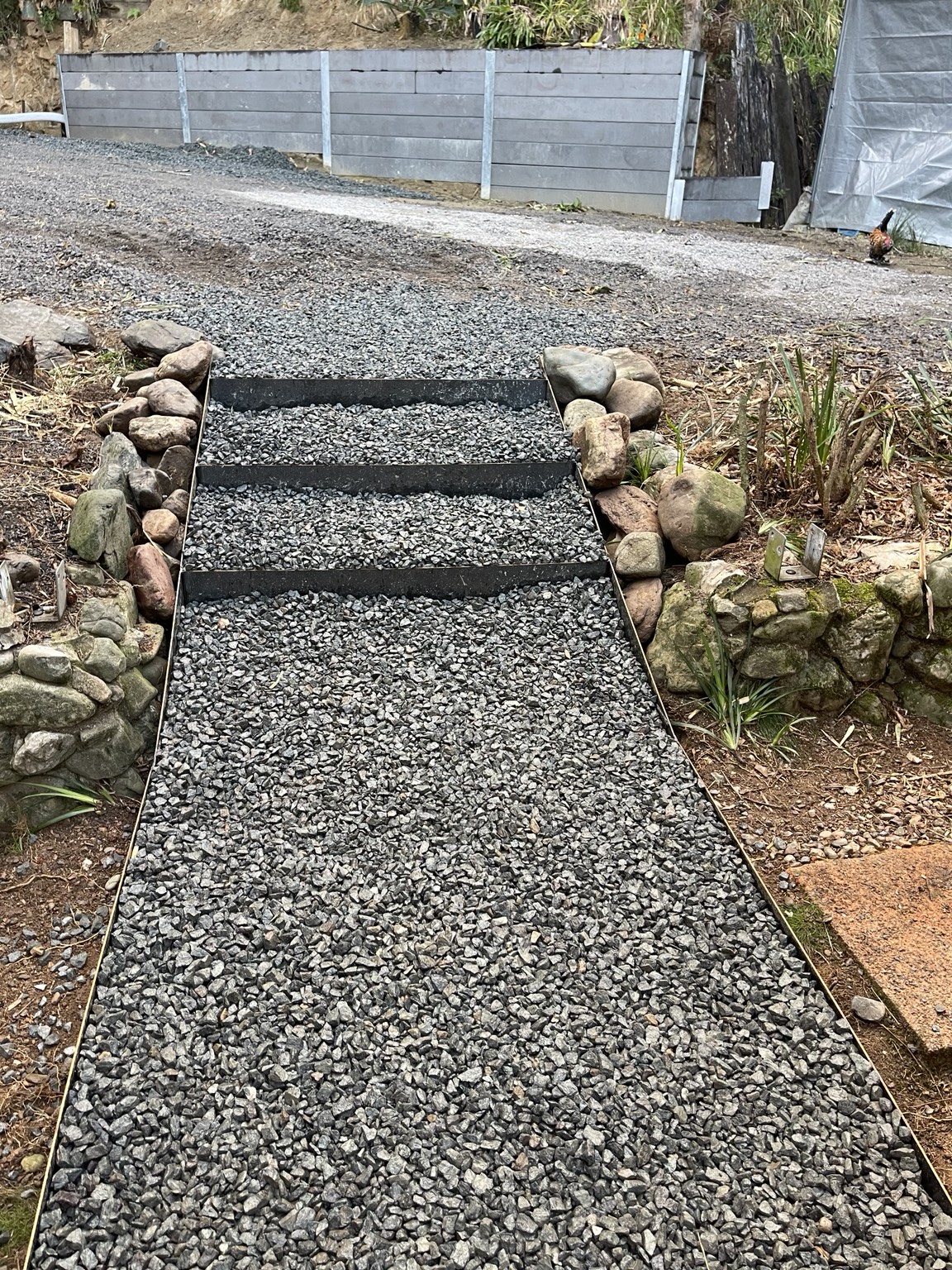 Finished gravel stair path leading to a concrete sleeper retaining wall
