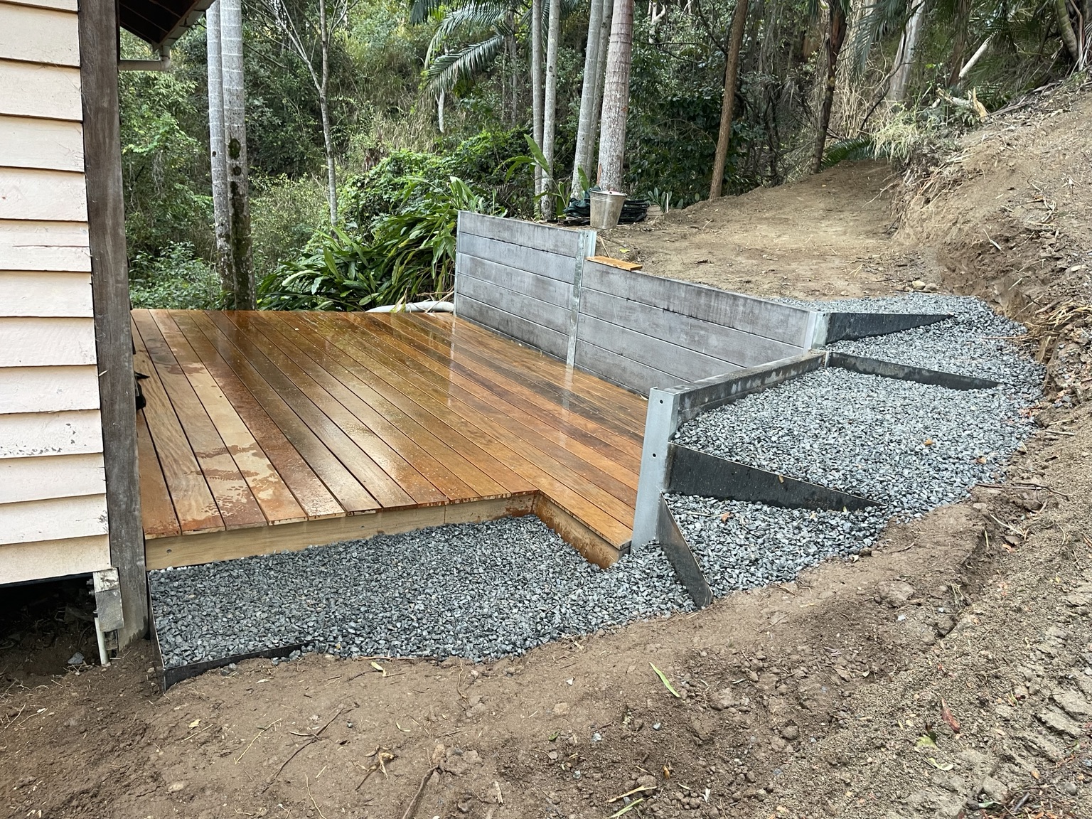 Timber deck, concrete sleeper retaining wall and gravel steps built into a steep site